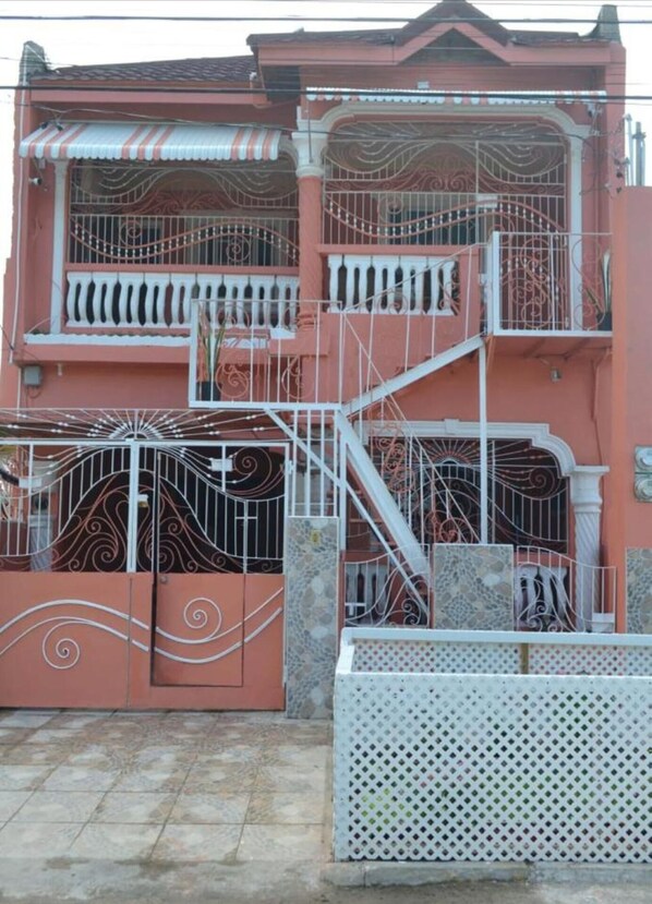 Un immeuble à plusieurs étages doté de balcons, d’un escalier et de rampes de protection en métal décoratives.