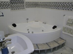 Une salle de bain avec une baignoire sur pieds, un lavabo et des carreaux décoratifs aux murs et sur le sol.