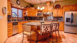 A kitchen with wooden cabinets, a stainless steel refrigerator, a microwave, and a large island with bar stools. - Casa Roja, a spacious 3-bedroom home (San Felipe)