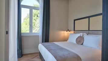 Un lit bien fait, avec une tête de lit, une fenêtre avec des rideaux et un luminaire fixé au mur.