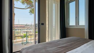 Ein Schlafzimmer mit großem Fenster und Blick auf den Außenbereich, ausgestattet mit einem Bett und einer braunen Bettdecke.