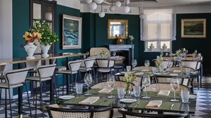 Un restaurant amb diverses taules i cadirees, una llar de foc i obres d'art a les parets.
