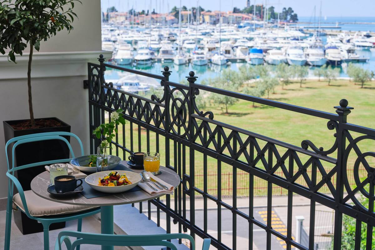 A balcony with a table set for breakfast, overlooking a marina with numerous boats.