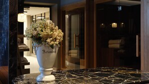 Un vas de ceràmica blanca amb flors sobre una taulella de marbre a la zona d'entrada d'un hotel.