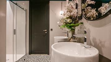 A bathroom with a large white sink, a dark door, and a mirror with flowers.