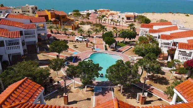 A resort with a central swimming pool, beach access, and Mediterranean-style architecture. - La Hacienda Condo Six (San Felípe)