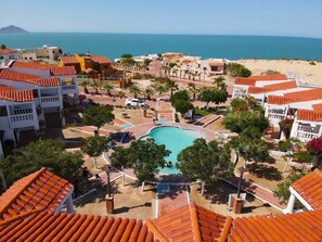 A resort with a central swimming pool, beach access, and Mediterranean-style architecture.
