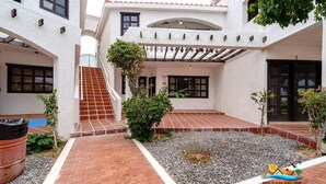 A courtyard with a tiled patio, a staircase, and a covered area with a pergola. - La Hacienda Condo Six (San Felípe)