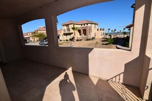 A covered outdoor area with a view of a residential neighborhood, including houses and a beach.