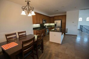 Una cocina moderna con armarios de madera, una isla central y un comedor con mesa y sillas.