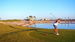 A golf course with a water hazard, a putting green, and a clubhouse in the background. - Condo 37-3 El Dorado Ranch (San Felipe)
