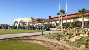 A golf course with a clubhouse, parked golf carts, and palm trees. - Condo 37-3 El Dorado Ranch (San Felipe)