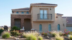 A two-story house with a stone facade, a balcony, and a landscaped garden with various plants and flowers. - Condo 37-3 El Dorado Ranch (San Felipe)