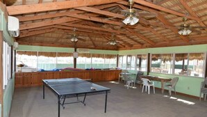 A spacious room with a ping pong table, wooden ceiling beams, and large windows. - Los Sahuaros House 34 (San Felipe)
