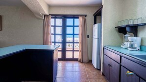 A kitchen with a refrigerator, a coffee maker, and a window with curtains. - La Hacienda Condo 18 (San Felípe)