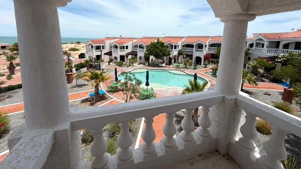 A pool area with a view of a resort building. - La hacienda condo Four (San Felípe)