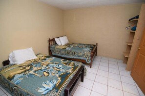 Quarto com duas camas, um guarda-roupa e soalho em azulejos.