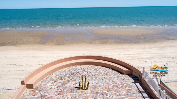 A beach view with a paved area featuring a cactus sculpture.