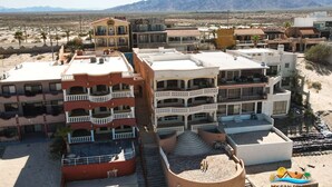 A multi-story hotel with balconies, a swimming pool, and a desert landscape in the background.
