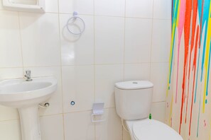 A bathroom with a white sink, toilet, and a wall with colorful drips. - IT16 Apt 2 Quartos a 150m da Praia (Camaçari)