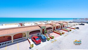Ein Hotel an der Küste mit mehreren Gebäuden, einem Strand im Hintergrund und blauem Himmel.