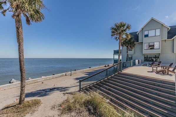 A beachfront property with a patio area, outdoor seating, and a view of the ocean.