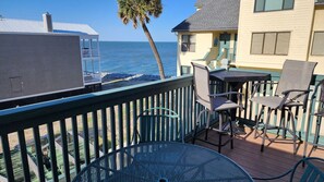 A deck with outdoor furniture overlooking the ocean.