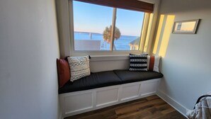 A window seat with cushions, a view of the sea, and a framed picture on the wall. - Ocean views includes Golf Cart - 611 Newhaven (Fripp Island)