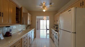 A kitchen with wooden cabinets, a refrigerator, a microwave, and a blender.