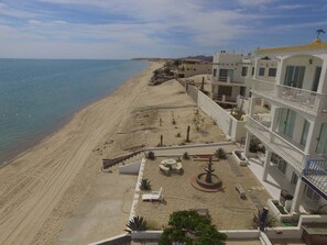Een strandhotel met een zandstrand, een zwembad en uitzicht op zee.