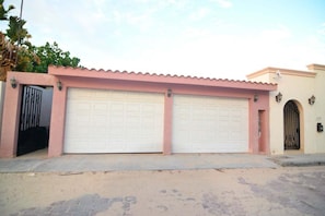 A two-story building with a pink facade and a white garage door.