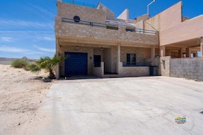 A two-story building with a blue garage door, a balcony, and a concrete driveway.