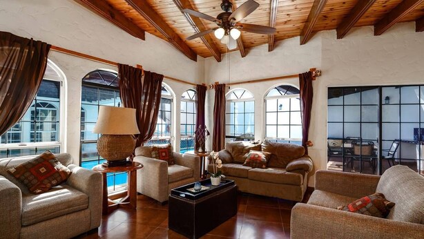 A spacious living room with a high ceiling, wooden beams, and large windows. There are multiple seating areas with sofas and a coffee table. - Rick`s Private POOL House (San Felípe)