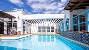 A swimming pool with a clear blue water surface, surrounded by a white building with arched windows and a blue railing. - Rick`s Private POOL House (San Felípe)