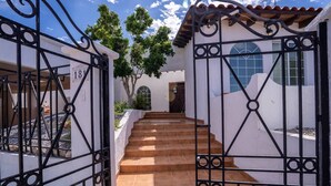 A gated entrance with a staircase leading to a building with a white facade and a tiled roof. - Rick`s Private POOL House (San Felípe)