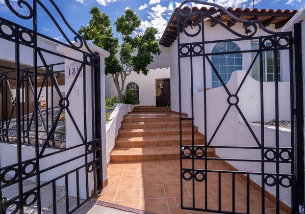 Enter through the ornate gate and approach the symmetrical building with a central arched window and door.