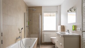 A modern bathroom with a bathtub, shower, toilet, and vanity. - Familienfreundlich - Farbenfroh - Außergewöhnlich (Braunlage)