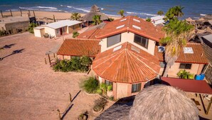 A coastal property with multiple buildings, a beach, and a thatched-roof structure.