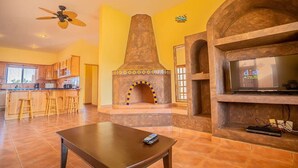 Un salon avec une cheminée, un téléviseur et un ventilateur de plafond.