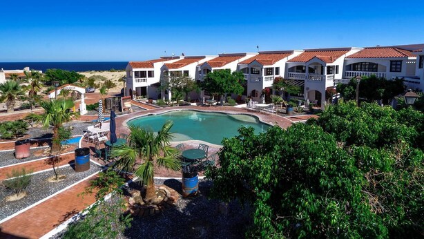 Een resort met een zwembad, meerdere gebouwen en uitzicht op de oceaan.