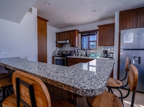 A kitchen with granite countertops, wooden cabinets, stainless steel appliances, and a window.