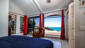 Une chambre avec un lit, une chaise et une vue sur la plage et l’océan.