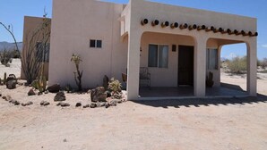 A desert-style building with a covered porch, a small window, and a door.