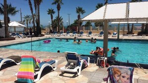 A swimming pool with lounge chairs and palm trees.