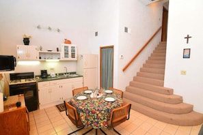A compact kitchen with a dining table, a stove, and a refrigerator.