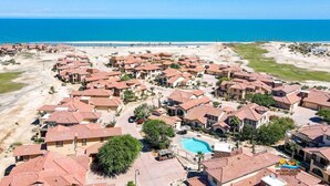 A coastal residential area with houses, a swimming pool, and a beach in the background. - Condo 24-1 El Dorado Ranch (San Felípe)