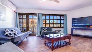 A living room with a sofa, armchair, coffee table, TV, and a large window with a view.