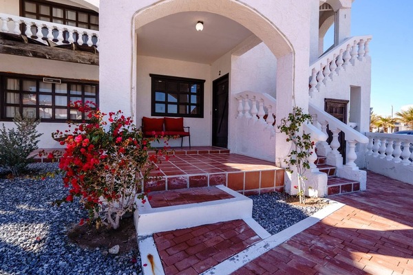 The gated community entrance requires an electronic access card for entry, located off Highway 5 approximately 9 km south of downtown San Felipe. A paved driveway leads to this two-story building.