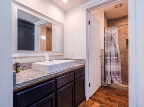 Bathroom features a large sink, mirror, and a shower area with a striped curtain.