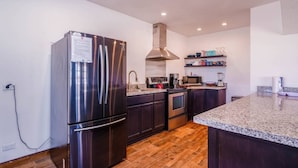A modern kitchen with stainless steel appliances, dark wood cabinets, and a granite countertop.